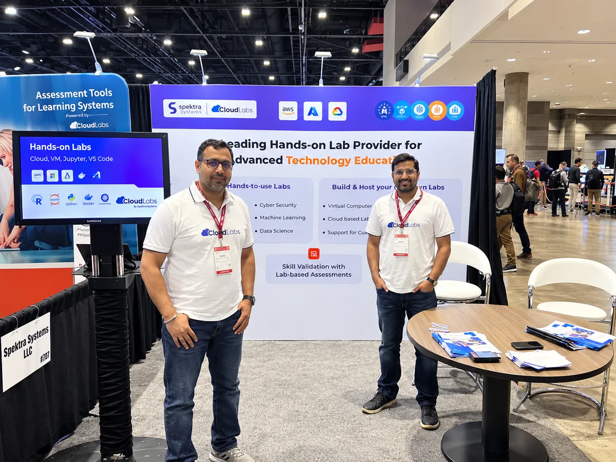 Two CloudLabs team members beside a monitor demonstrating cloud, VM, Jupyter and VS Code hands-on labs at the Spektra Systems stand